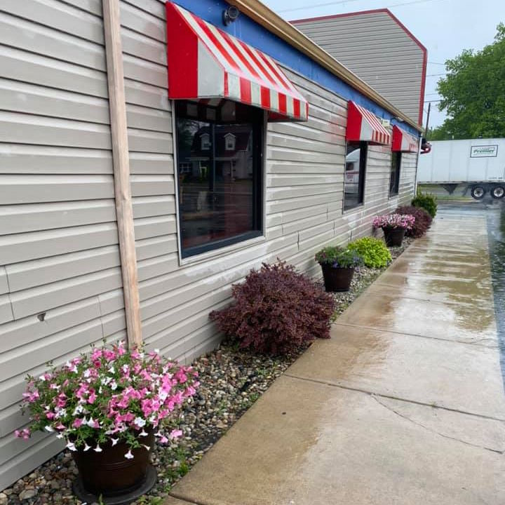 side of restaurant building showing flowering landscape along sidewalk entrance